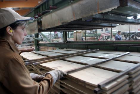 Factory worker piling timber products